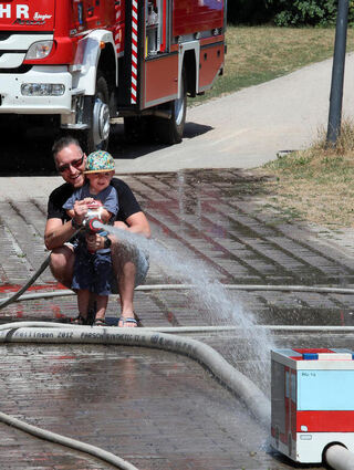 Erik Hein und Fritz (3) bei den Wasserspielen am Stand der Feuerwehr.
