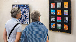 Die Gäste der Vernissage schauen sich interessiert die vielen Details der Werke von Hilli Gebert an.