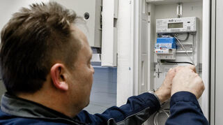 Ein Elektriker montiert einen digitalen Stromzähler mit einem Smart-Meter-Gateway zur Datenübertragung.