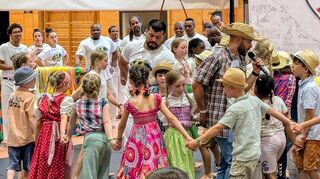 „Cao“ in Karohemd mit Strohhut moderiert den Tanz der Landleute zum Fest für den Heiligen Johannes.