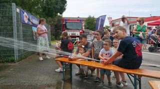 Ganz gebannt vom Löschangriff: Die drei Brüder Luca (v. l.), Jonas und Nico sind von den Wasserspielen begeistert, während um sie herum die Jugendfeuerwehr und weitere Familien für Unterstützung sorgen.