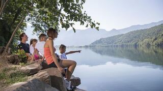 Eine Familie genießt bei einer Wanderung die Aussicht auf den Levicosee, einer der wärmsten Seen Oberitaliens.