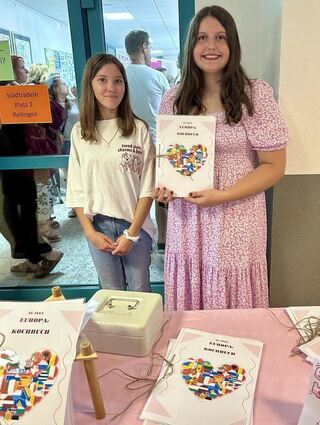 Nadja und Yasmin aus der neunten Klasse präsentieren ihr Rezeptbuch mit verschiedenen europäischen Spezialitäten.