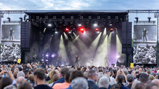 Stilsicherer Bühnenauftritt von Bryan Adams mit seiner Band: Die Show wird auf den Videoleinwänden vorwiegend in Schwarzweiß begleitet.
