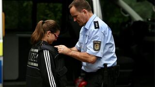 Hauptkommissar Michael Keller vom Polizeipräsidium Mannheim hilft beim Anlegen der Schutzweste und erklärt dabei, für was sie benötigt wird.