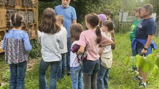 Imker Günter Martin (hinten l.) erklärt den Ferienkindern, welche Leistung die Bienen bei der Bestäubung von Pflanzen erbringen und wie ihr Zusammenleben funktioniert.