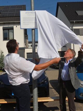Dr. Dr. Ulrich Mende (rechts) enthüllt gemeinsam mit Bürgermeister Nils Drescher die Tafel, auf der beschrieben ist, was zur Namensgebung für den Platz führte.