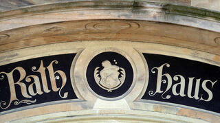 Die Außenansicht des Rathauses mit dem Gemeindewappen über der Tür.