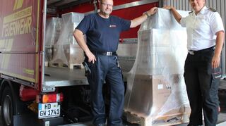 Ralf Innetsberger (Feuerwehr Schwetzingen) und Stefanie Heck, Leiterin des Amts für Feuerwehr und Katastrophenschutz im Landratsamt Rhein-Neckar-Kreis, beim Verladen eines der Musterausstattungssets für Notfalltreffpunkte.