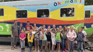 Hanspeter Rausch, Renate Hettwer, Marco Kappes und Charlotte Backes gemeinsam mit den kleinen Forschern vor dem Ökomobil.