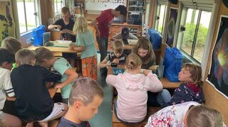 Im fahrenden Klassenzimmer untersuchen die Jungen und Mädchen den Inhalt des Wassers.