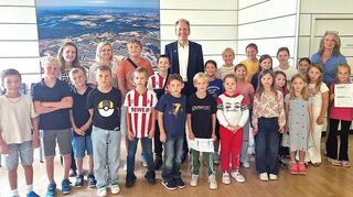 Alle Ferienkinder in Startaufstellung zur Rathaus-Rallye mit Bürgermeister Dr. Ralf Göck (Mitte) und Mitarbeiterin Marion Thüning (r.), gesamtverantwortlich für das Kinderferienprogramm, sowie Marie Schäfer und Ivona Szutra im Sitzungssaal des Rathauses.