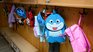 Kinderrucksäcke hängen in der Garderobe einer Kita.