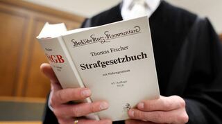 Symbolbild: Ein Richter hält eine Kommentarfassung zum Strafgesetzbuch in der Hand.