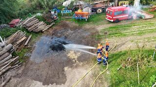 Die Jugendlichen löschen gemeinsam brennendes Holz bei einem Landwirtschaftsbetrieb.