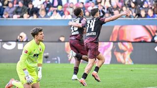 Augsburgs Torwart Finn Dahmen kauert bedröppelt am Boden, die Leipziger Assan Quedraogo (M) und Christoph Baumgartner (r) bejubeln das 0:5.