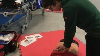 Ein Jugendlicher übt an einer Puppe, einen Menschen zu reanimieren.