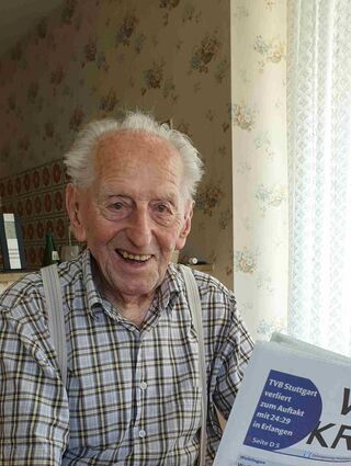 Karl Haidle sitzt an seinem 104. Geburtstag an einem Tisch und liest Zeitung.