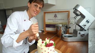 Maria Dornecker ist Konditormeisterin aus Lampertheim. Hier verziert sie eine Frischkäse-Himbeer-Torte mit dem Spritzbeutel.