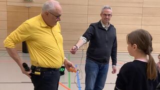 Sobald die Schülerin die Faust ballt, erhält Schulleiter Marcus Roth (M.) dank Jo Heckers (l.) Versuchsaufbau elektrische Impulse - sehr zum Spaß der Zuschauer.