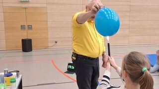 Wenn der Luftballon mit Wasser gefüllt ist, passiert nichts, wenn eine Schülerin ihn mit dem Feuerzeug erhitzt.